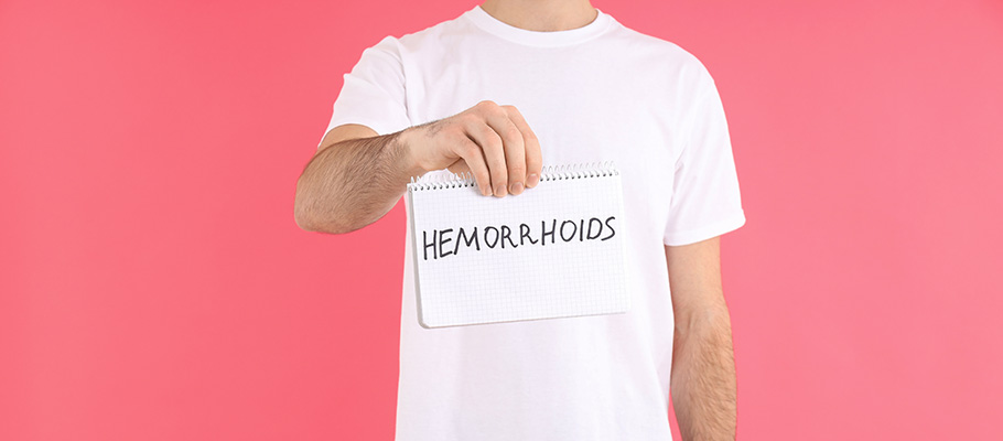 Persona sujetando un cartel donde puede leerse "hemorroides"