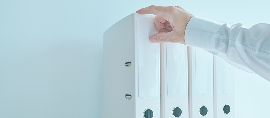 Mano-de-hombre-cogiendo-una-carpeta-blanca-de-una-estantería-