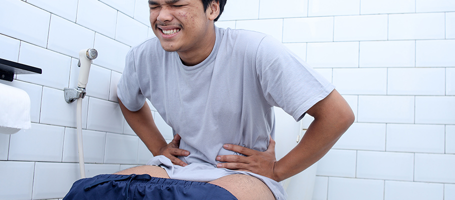 Hombre-sentado-en-inodoro-con-signos-de-dolor