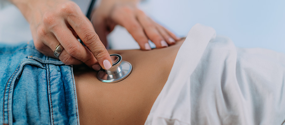 Gastroenterólogo realizando un examen abdominal con estetoscopio